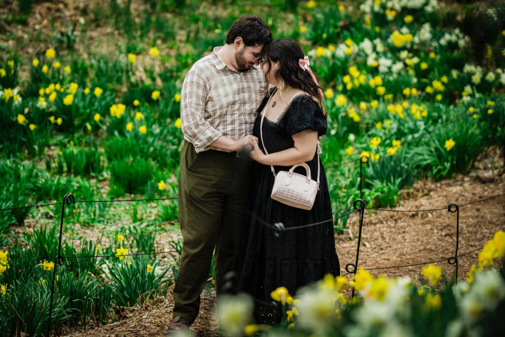 Engaged couple touching foreheads together on daffodil garden path at Reeves-Reed Arboretum NJ