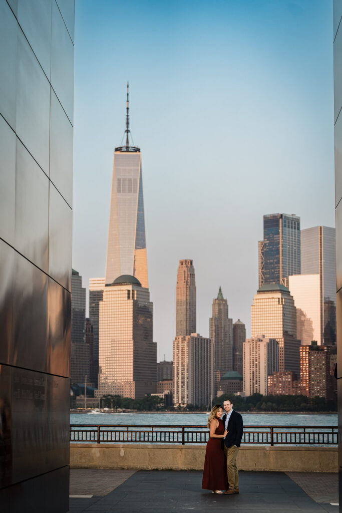 Couple framed between the Empty Sky Memorial walls with NYC skyline during Liberty State Park engagement photos