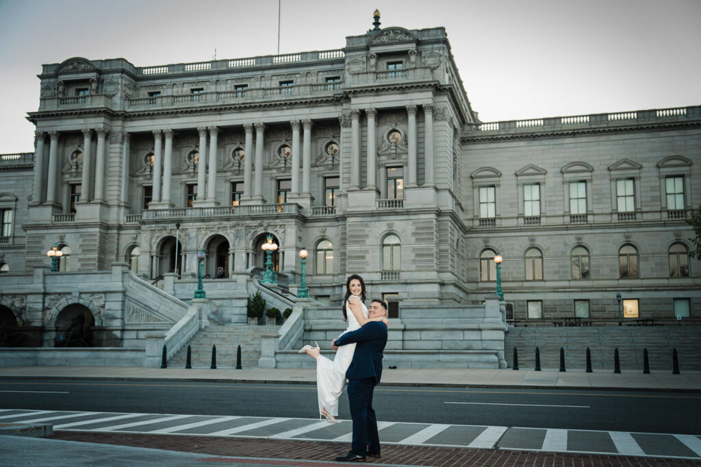 Man lifting his laughing partner in the street in front of the Library of Congress at sunrise Washington DC