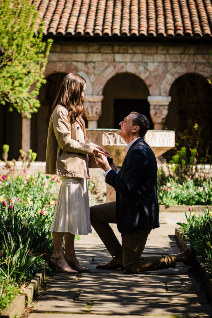 Man proposing on one knee in the Cuxa Cloister garden courtyard at The Met Cloisters NYC