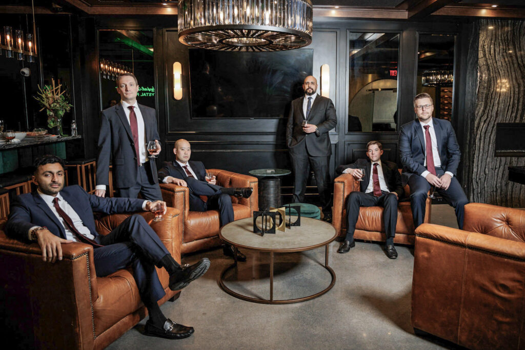 Groomsmen in dark suits relaxing in Crystal Plaza lounge before multicultural wedding ceremony