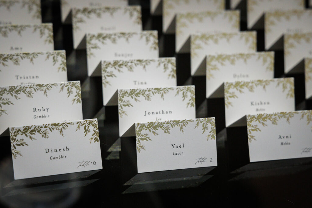 Wedding escort cards with gold botanical design displayed at multicultural Crystal Plaza reception