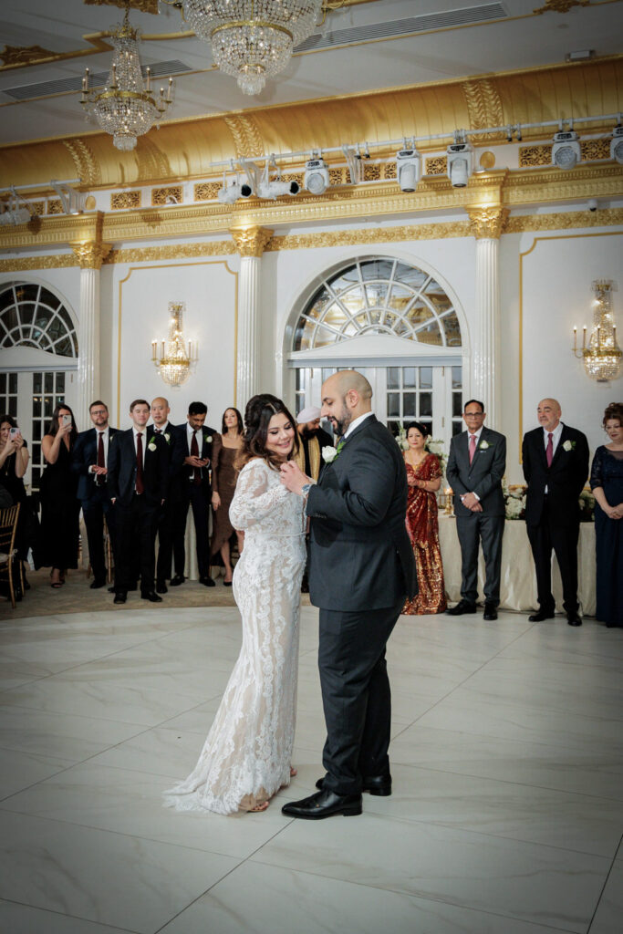 Newlywed couple sharing first dance in Crystal Plaza gold ballroom surrounded by wedding guests