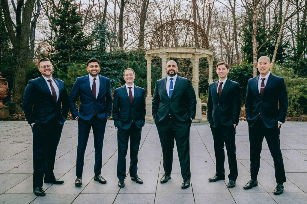 Diverse wedding party groomsmen standing together outside stone gazebo at Crystal Plaza New Jersey