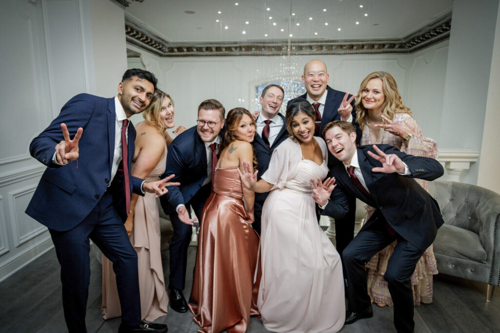 Wedding party posing playfully with peace signs at multicultural wedding Crystal Plaza NJ