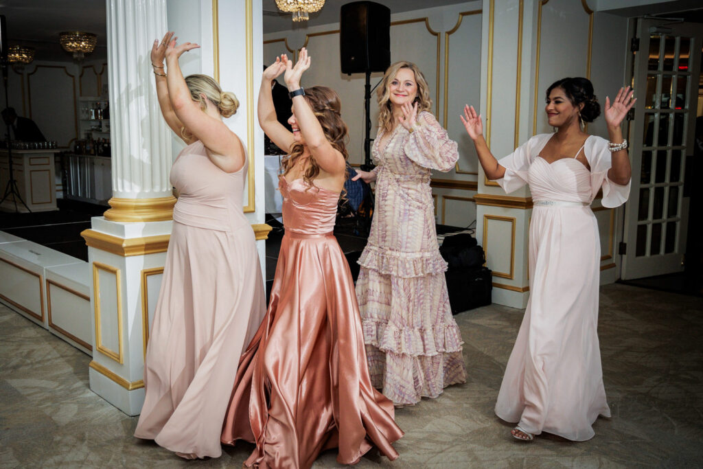 Bridesmaids in blush and rose gowns dancing joyfully at multicultural wedding reception Crystal Plaza