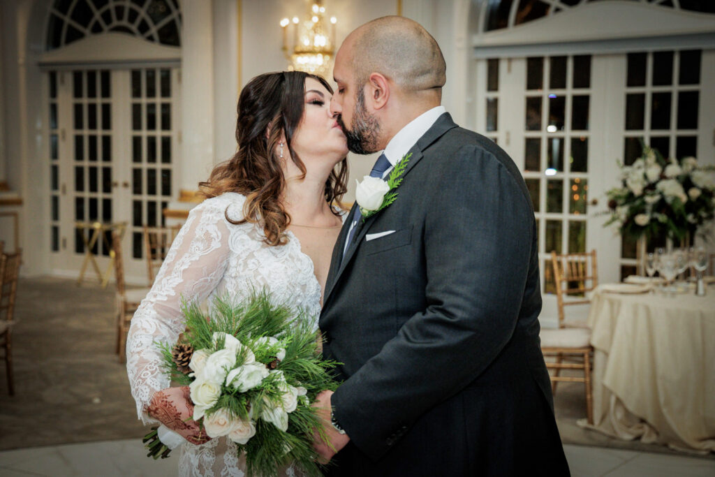 Newlywed couple sharing a kiss in Crystal Plaza ballroom during multicultural wedding reception