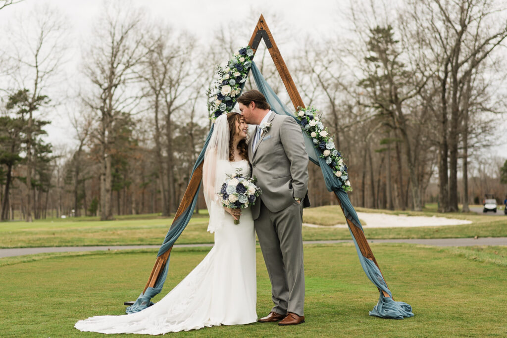 Bride and groom portrait under geometric wooden triangle arch at Pinelands Golf Club Hammonton NJ