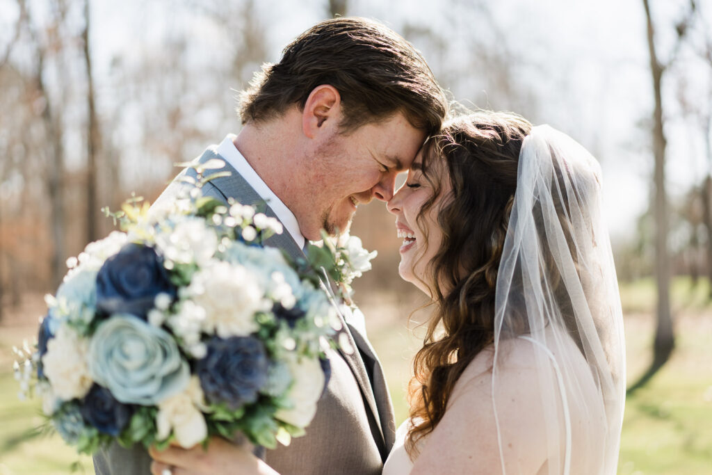 Bride and groom laughing with foreheads together bouquet in foreground at Pinelands Golf Club NJ wedding
