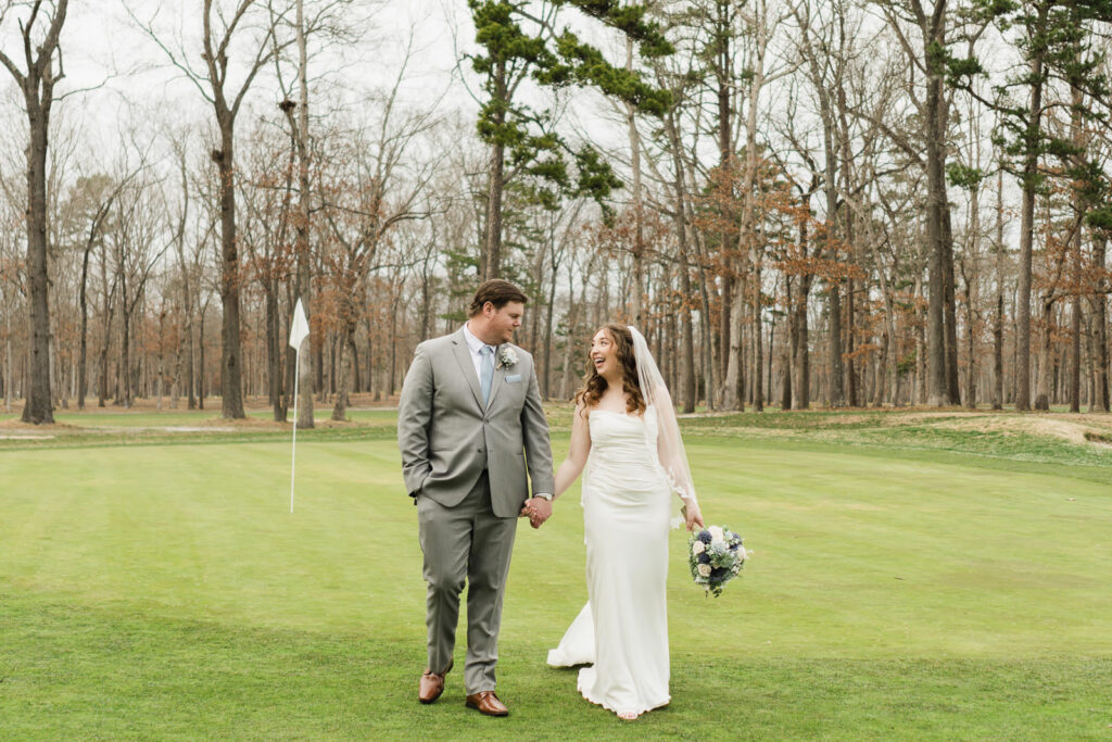 Bride and groom holding hands walking on golf green at Pinelands Golf Club New Jersey wedding