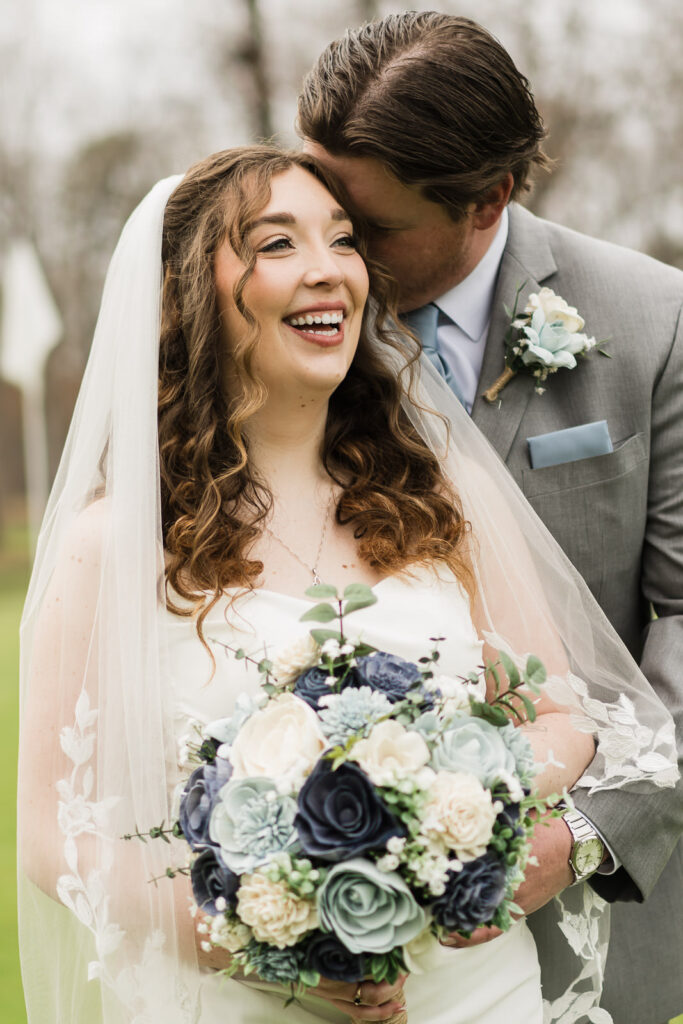Groom kissing bride on temple during close-up portrait at outdoor New Jersey golf club wedding