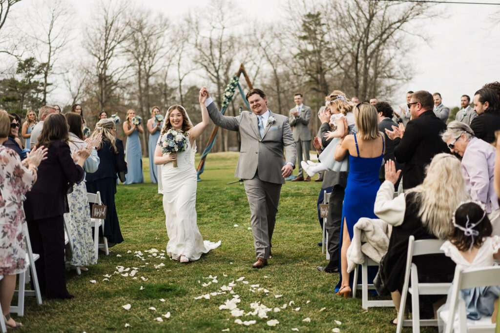 Bride and groom celebrating with raised arms during wedding recessional at Pinelands Golf Club Hammonton NJ