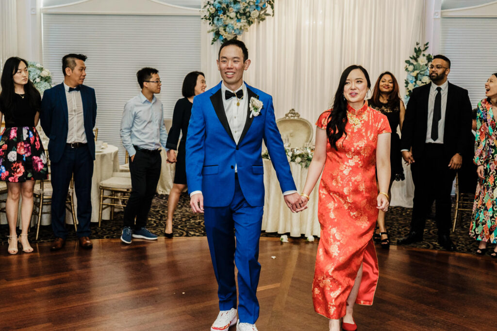 Bride and groom walking hand in hand onto the Crystal Plaza dance floor during their reception entrance in Livingston NJ