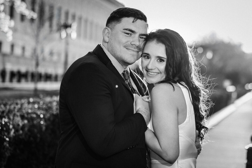 Black and white close portrait of couple holding each other with wind in her hair near the Supreme Court Washington DC