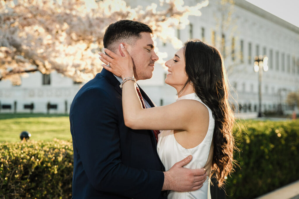 Couple nearly kissing surrounded by cherry blossoms near the Supreme Court Washington DC