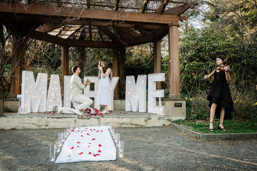 Wide proposal shot with man kneeling and violinist performing at Van Vleck House Gardens NJ