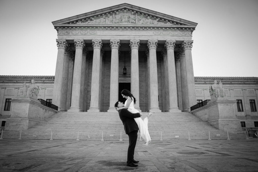 Black and white photo of man lifting his partner in front of the US Supreme Court Washington DC