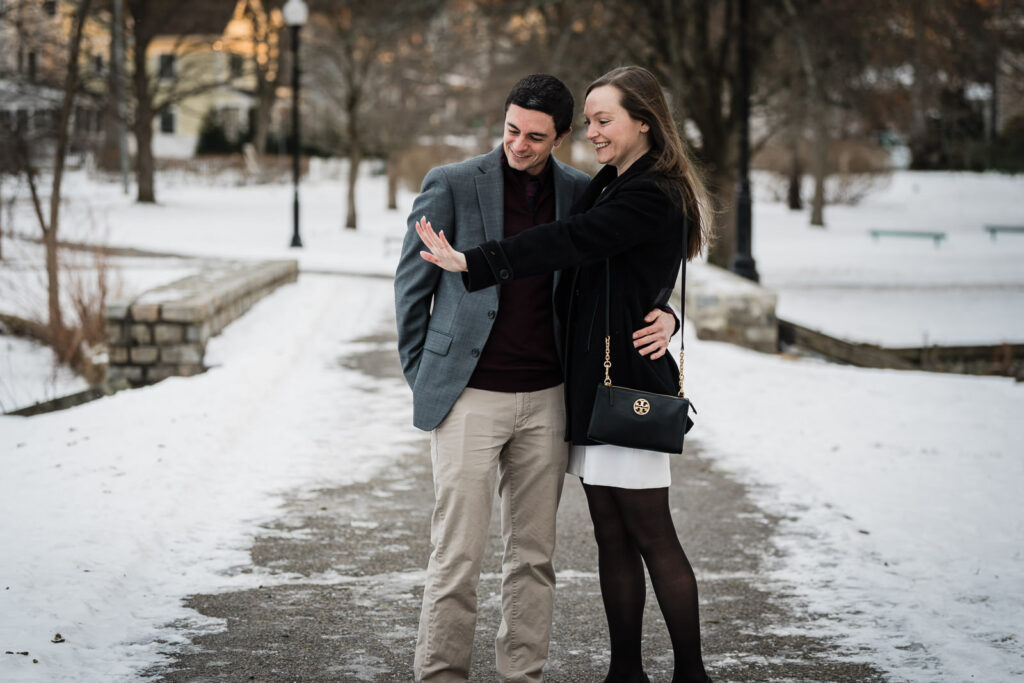 Newly engaged couple smiling and embracing on a snowy path at Verona Park NJ