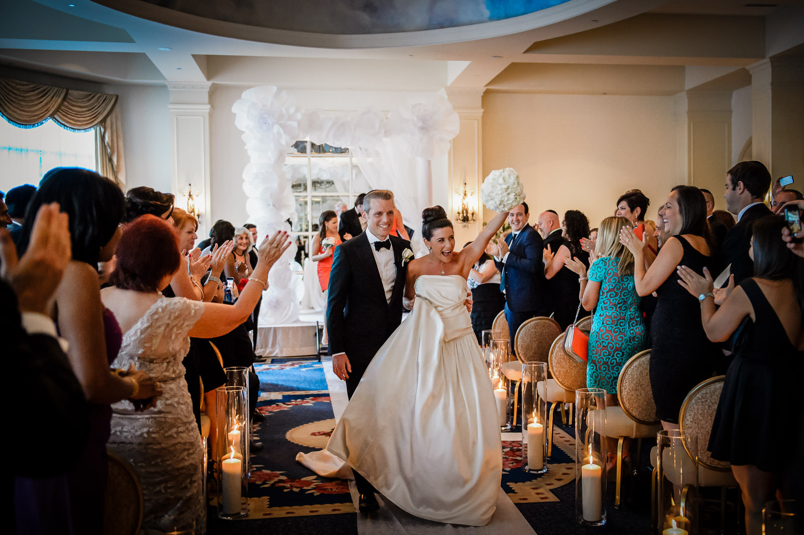 Bride and groom celebrating during authentic wedding recessional while guests cheer indoors in New Jersey wedding venue.