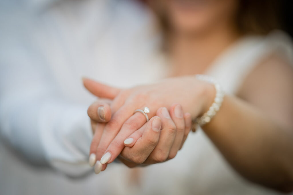 Close-up detail of a newly engaged couple holding hands gently showing a diamond engagement ring after a romantic outdoor proposal in New Jersey