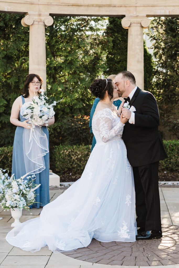 Bride and groom first kiss under stone columns at Macaluso's wedding venue Hawthorne NJ