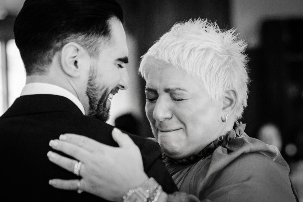 Emotional black and white moment between groom Otari and a tearful
family member sharing a heartfelt embrace after the Waterloo Village
wedding ceremony in New Jersey