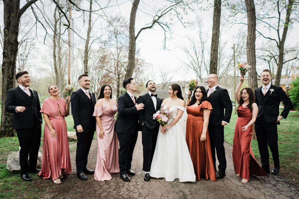 Kiara and Otari's wedding party laughing together in a candid moment
during outdoor portraits at Waterloo Village wedding in New Jersey