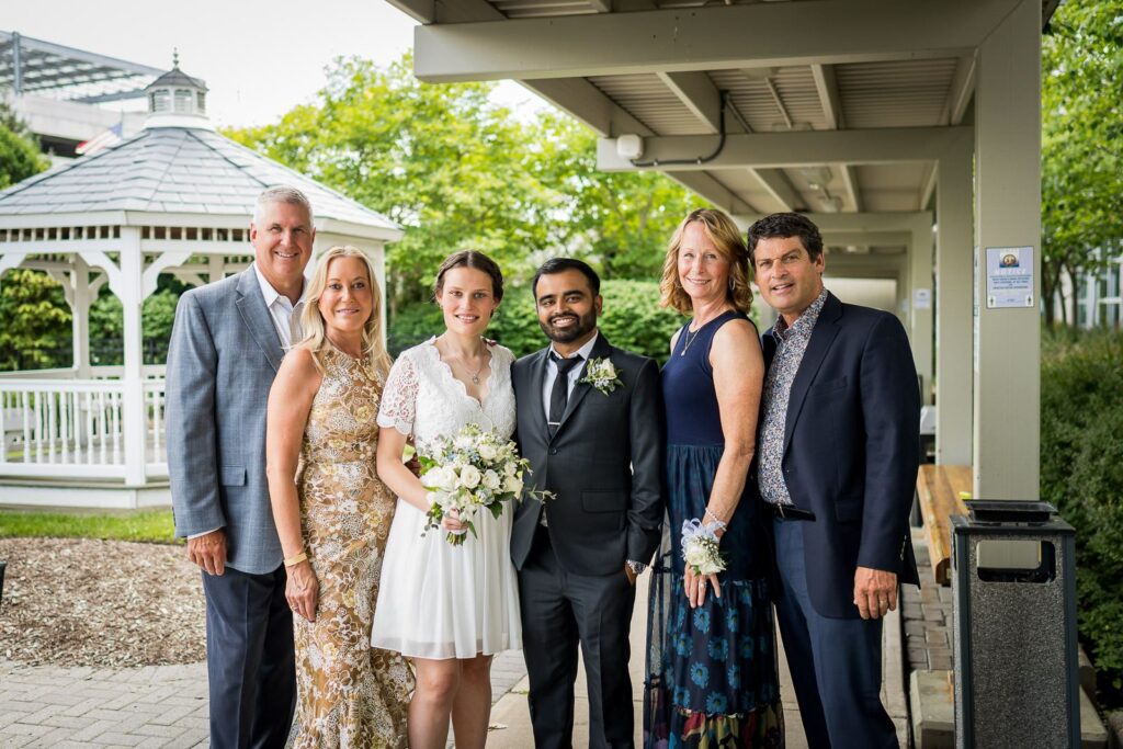 Newlywed couple and family posing for group portrait at Bergen County Plaza gazebo after courthouse wedding in Hackensack New Jersey