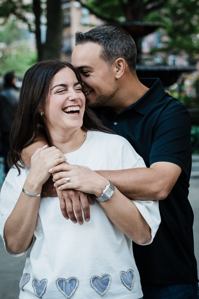 Engaged couple laughing together in a candid embrace during a West Village engagement session