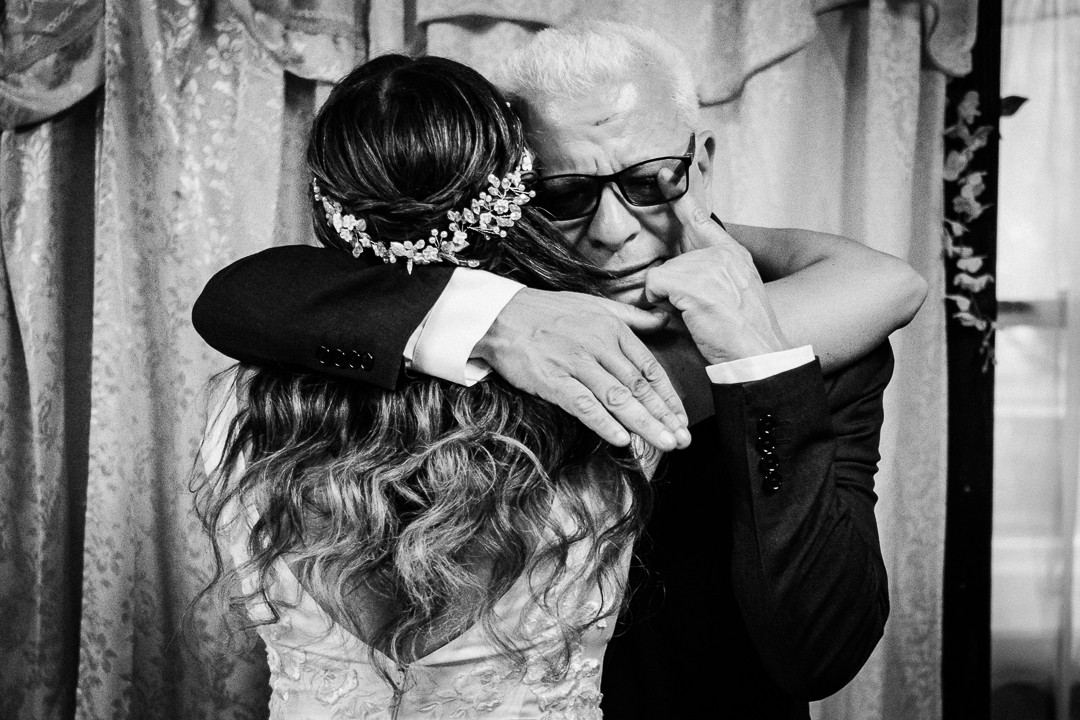 Father wiping away tears while embracing his daughter during an emotional getting-ready moment in New Jersey