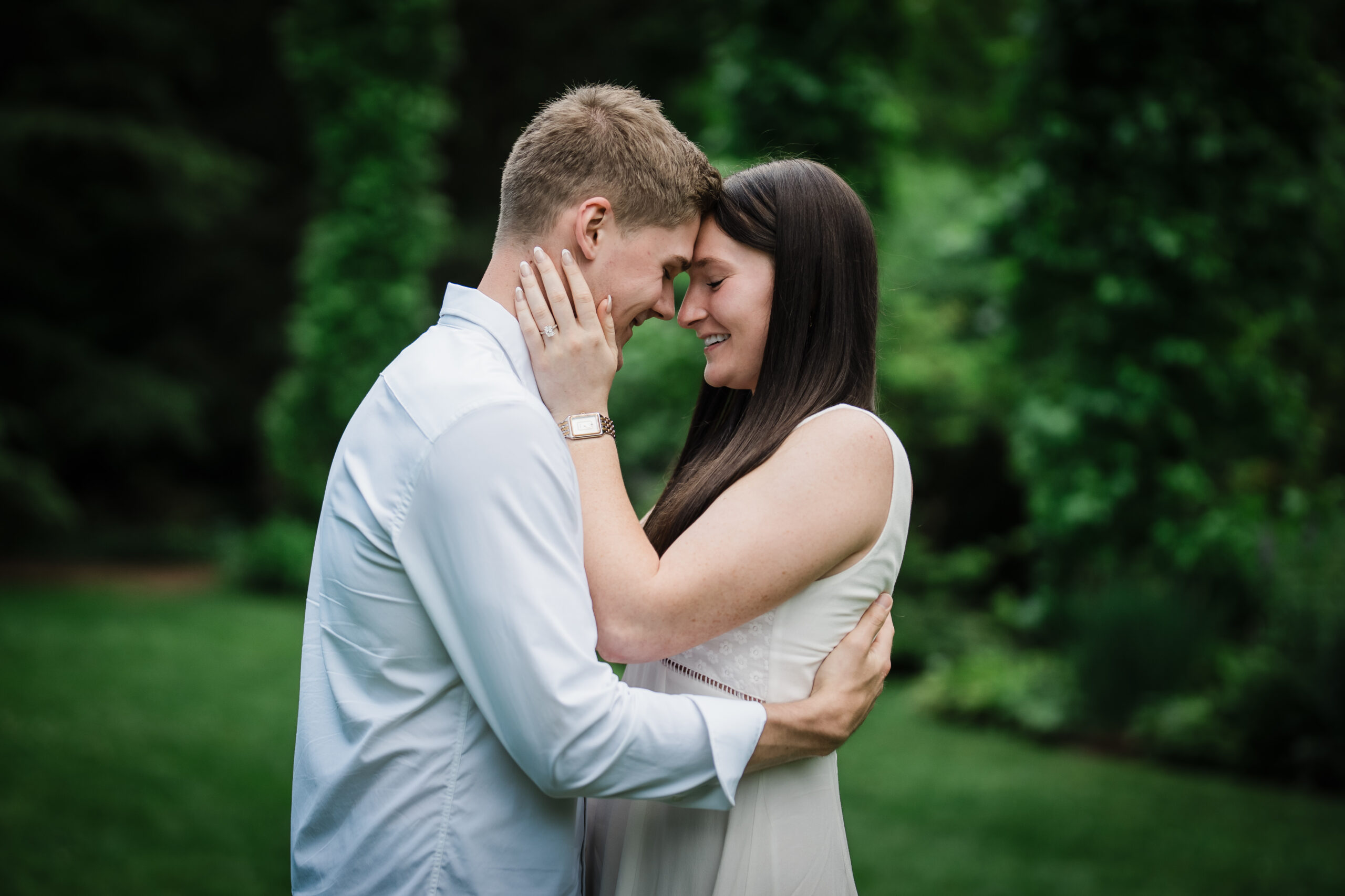 Engaged couple resting foreheads together with the engagement ring visible at Van Vleck Gardens