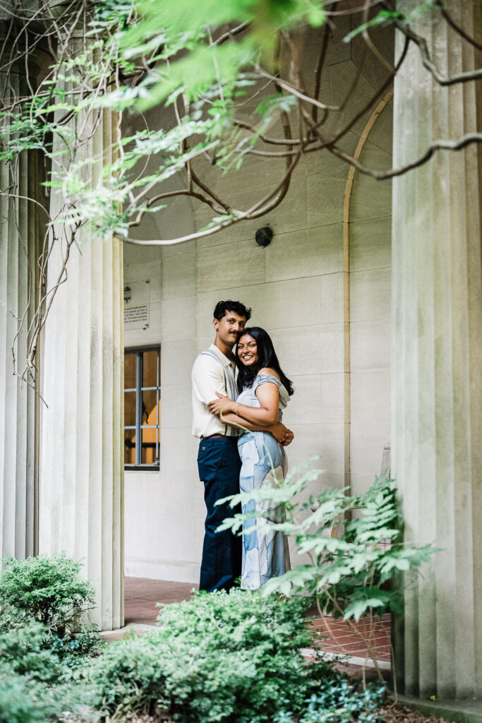 Engaged couple embracing beneath stone columns at Van Vleck House & Gardens Montclair NJ