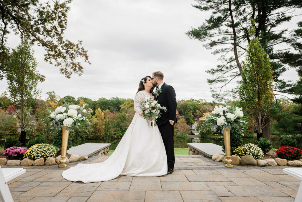 Newlyweds kissing among autumn trees during a wedding at Ramsey Country Club in New Jersey.