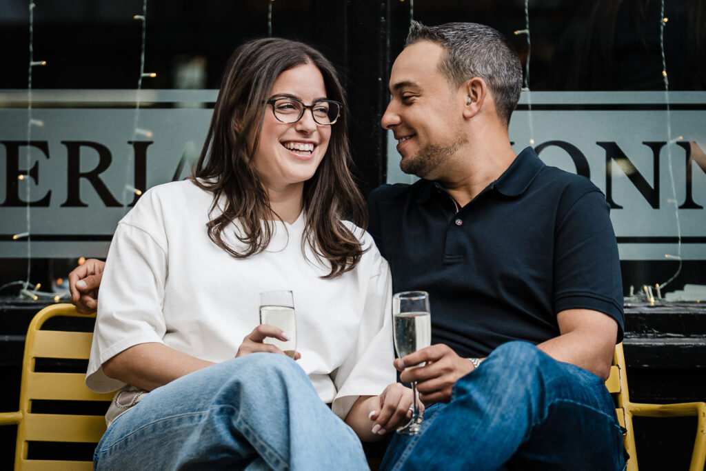 Engaged couple seated outside Osteria Nonnino during a West Village date-night engagement session