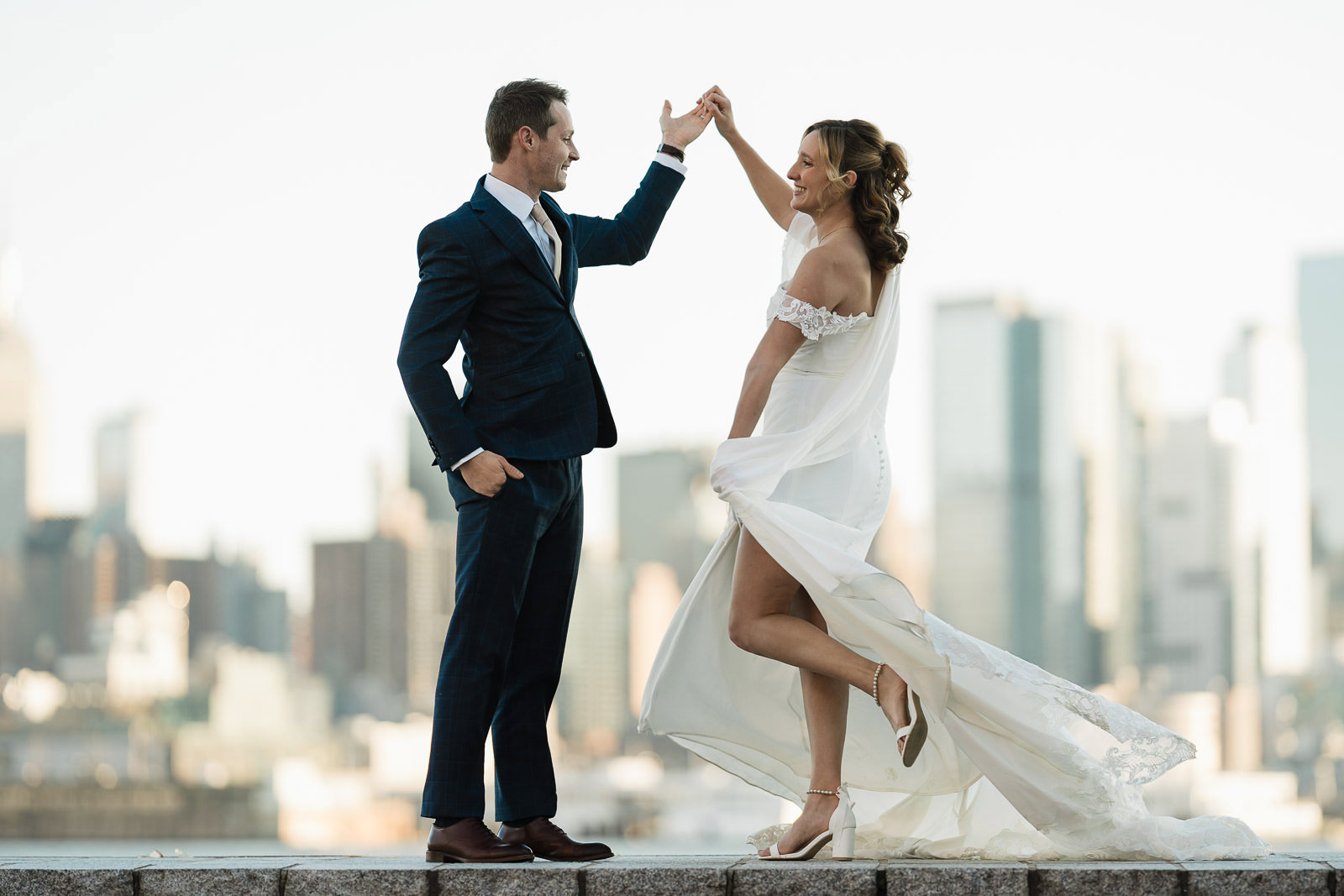 Bride and groom twirling at golden hour with the Manhattan skyline behind them