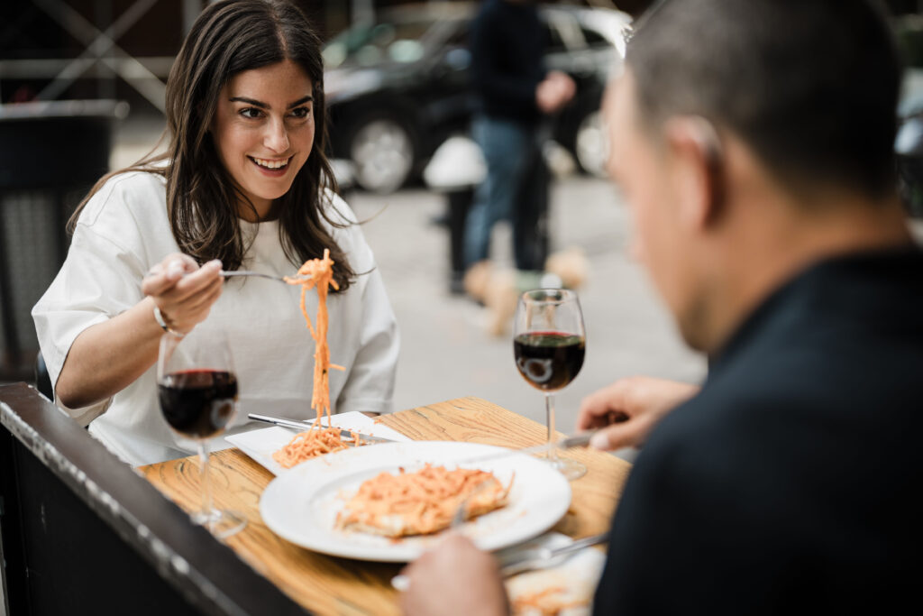 Engaged couple sharing wine and conversation outdoors at Osteria Nonnino during a New York City engagement session