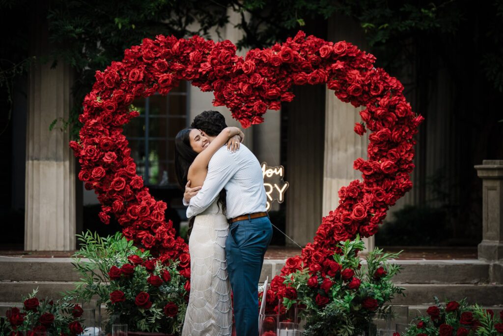 Engaged couple embracing beneath a custom floral heart at Van Vleck House in New Jersey