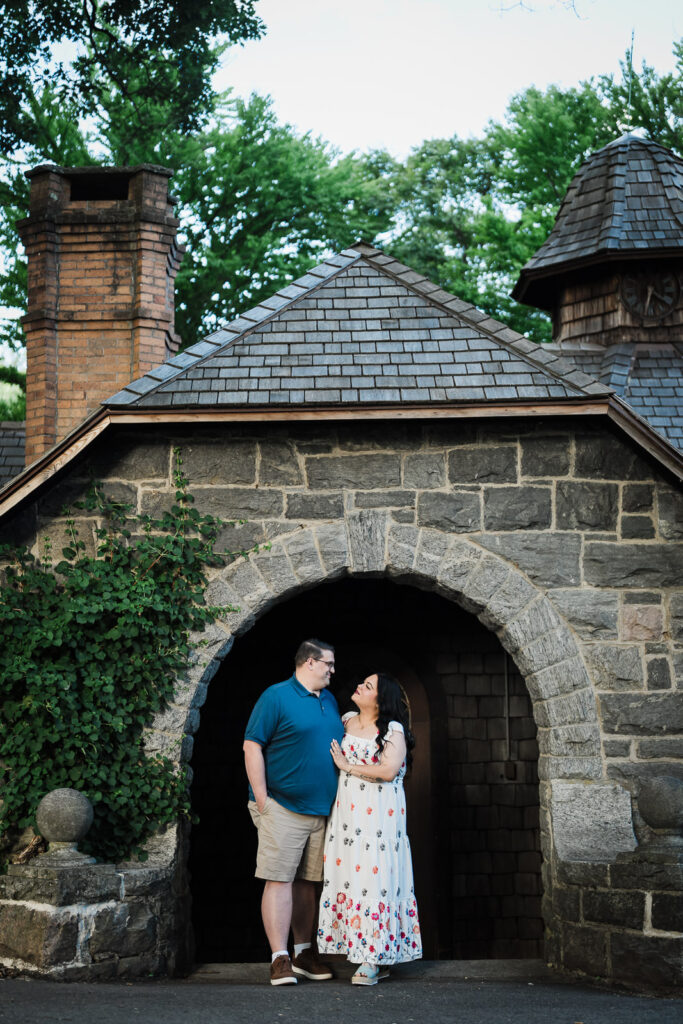 Engaged couple centered under a historic stone arch at Skylands Manor in Ringwood New Jersey
