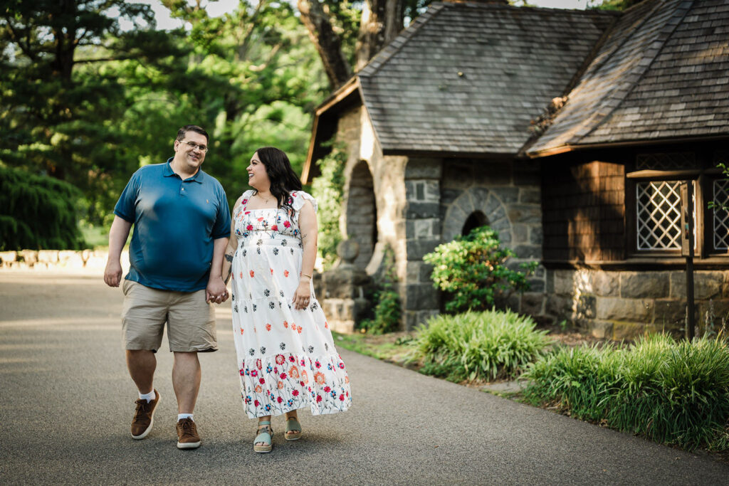 Engaged couple walking past a stone cottage during a Skylands Manor session
