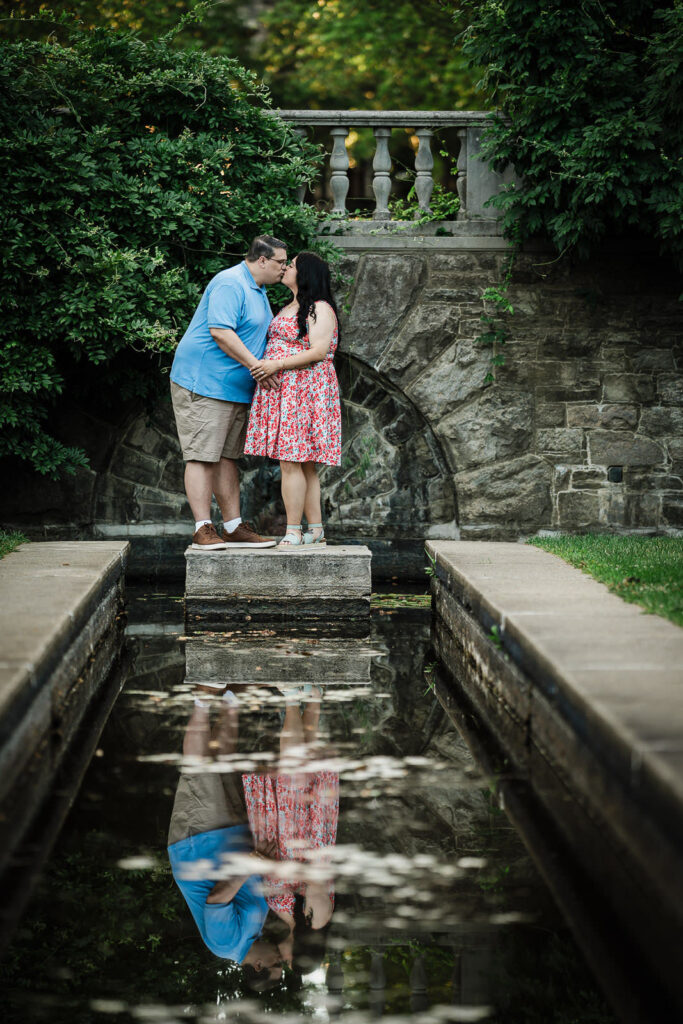 Engaged couple kissing on the stone reflecting-pool steps at Skylands Manor Ringwood