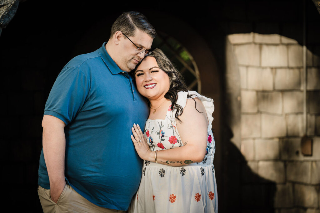 Engaged couple lit dramatically beside a stone tower wall at Skylands Manor Ringwood