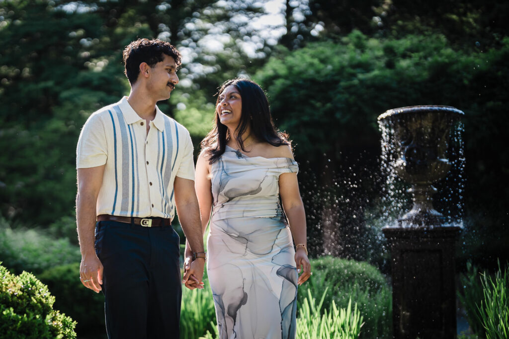 Engaged couple holding hands by a fountain at Van Vleck Gardens in Montclair NJ