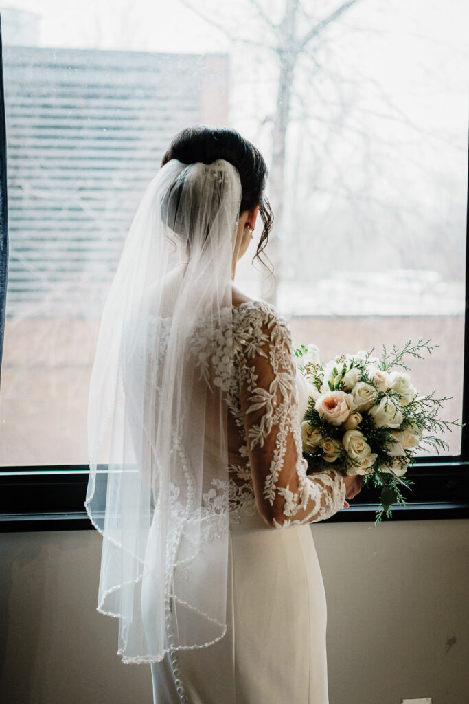 Bride in soft window light holding her bouquet before a New Jersey wedding ceremony
