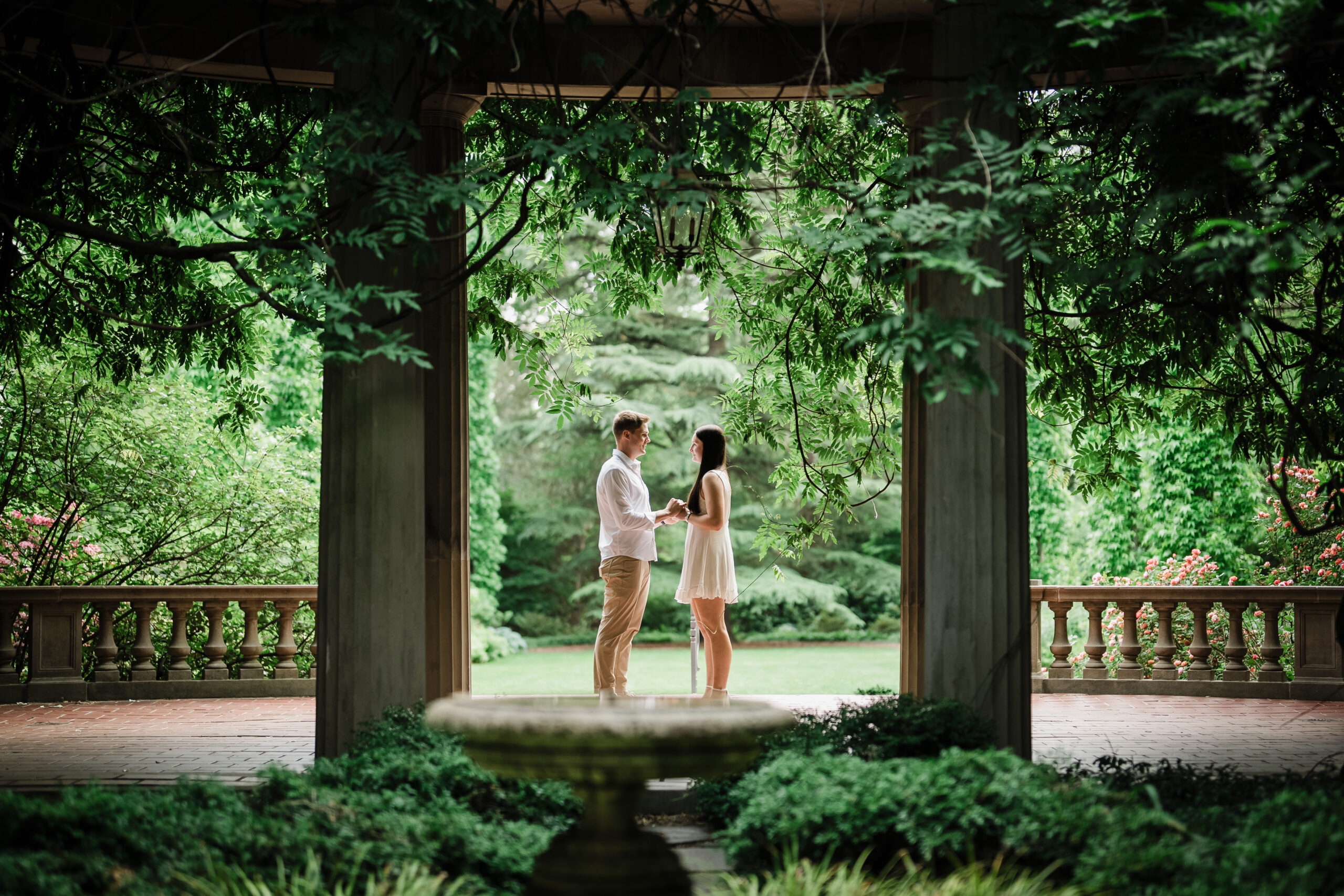 Couple holding hands beneath a wisteria-covered colonnade at Van Vleck House & Gardens in Montclair NJ
