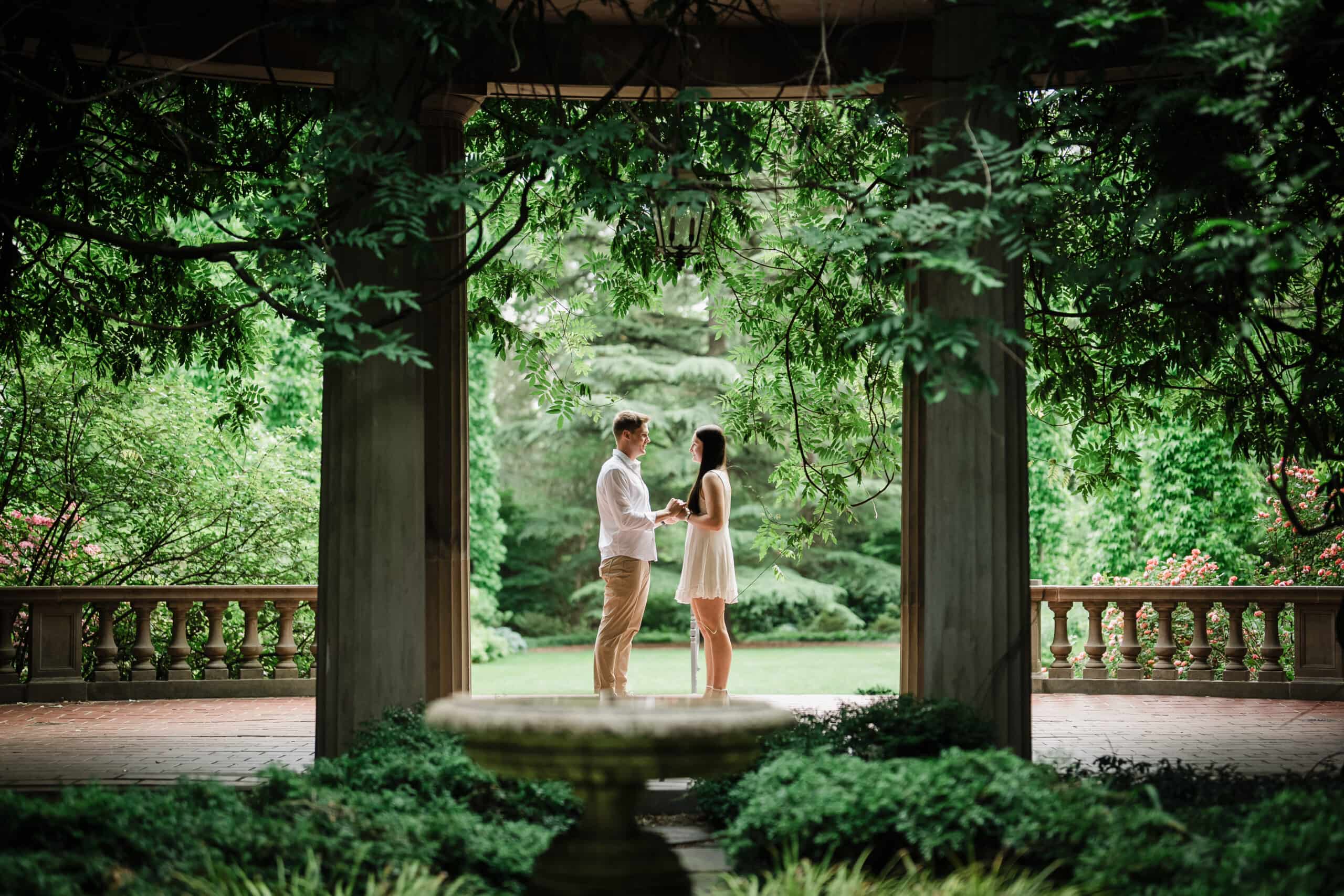 Couple holding hands beneath a wisteria-covered colonnade at Van Vleck House & Gardens in Montclair NJ