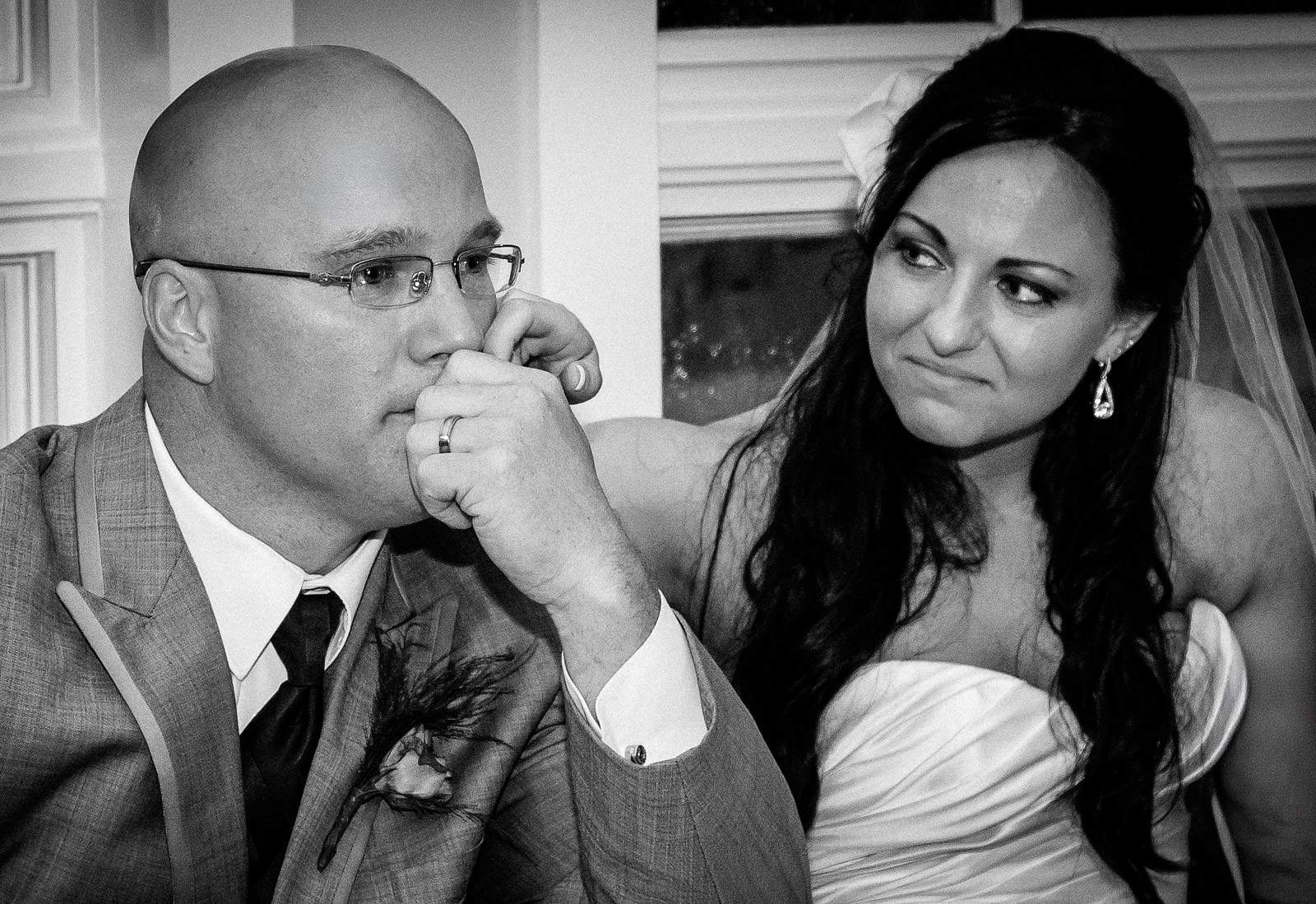 Black and white wedding photo of an emotional groom kissing his bride's hand during a reception toast at a New Jersey wedding