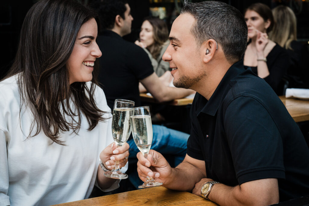 Couple toasting with red wine at Osteria Nonnino during their West Village date-night engagement session