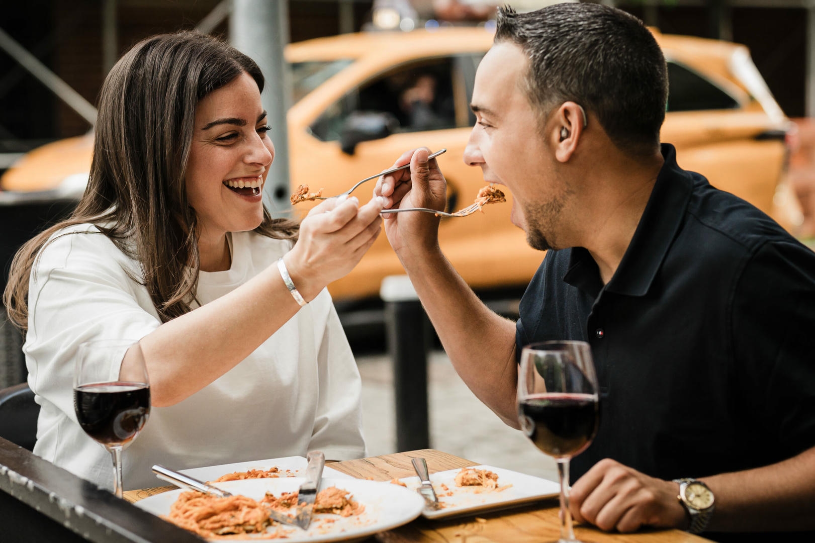 Engaged couple laughing while sharing a bite at Osteria Nonnino during a West Village engagement session