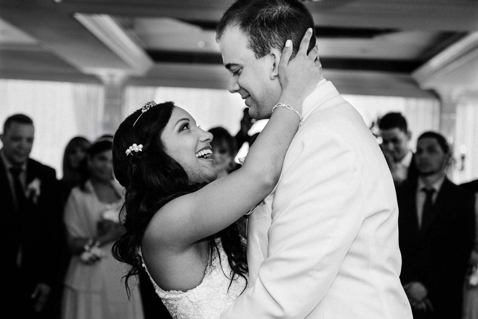 Bride laughing with her groom during their first dance at an elegant wedding reception.