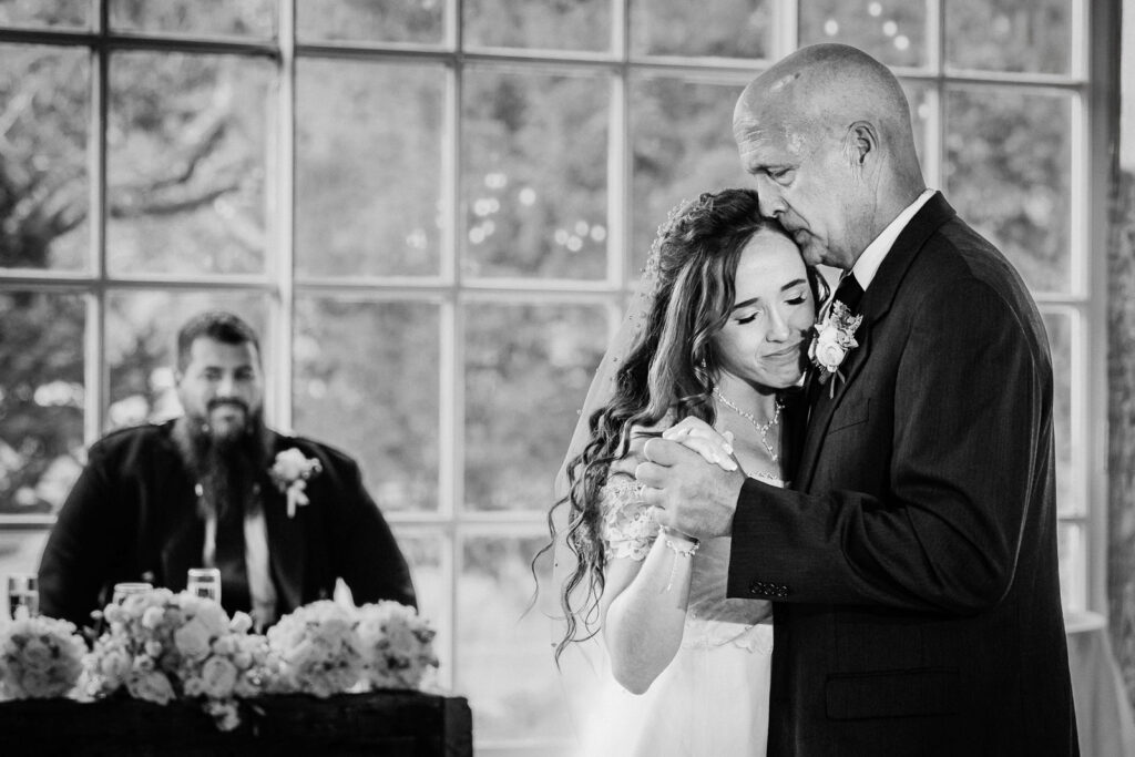 Father and daughter share an emotional dance during a wedding reception celebration.